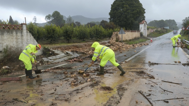 epa11690258 Several workers cleans the approach road to the village of Manuel after torrential rainfalls, in Valencia, eastern Spain, 29 October 2024. Heavy rains are hitting the region during the day.  EPA/NATXO FRANCES