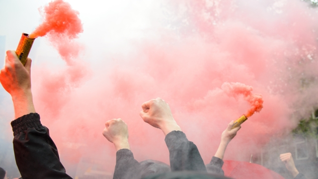 Soccer fans holding up fireworks with thick red smoke of bengal fire