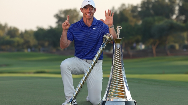 DUBAI, UNITED ARAB EMIRATES - NOVEMBER 17: Rory McIlroy of Northern Ireland poses with the DP World Tour Championship trophy and the Race to Dubai trophy on the 18th green whilst gesturing 'six' for his sixth Race to Dubai title, on day four of the DP World Tour Championship 2024 at Jumeirah Golf Estates on November 17, 2024 in Dubai, United Arab Emirates. (Photo by Richard Heathcote/Getty Images)