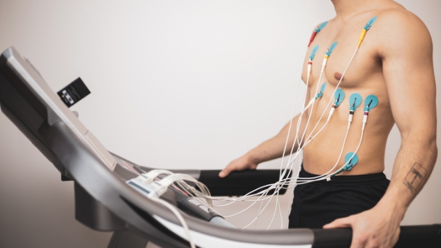 Un giovane atleta si sottopone a un test da sforzo su tapis roulant, monitorando l`attività cardiaca con un elettrocardiogramma.