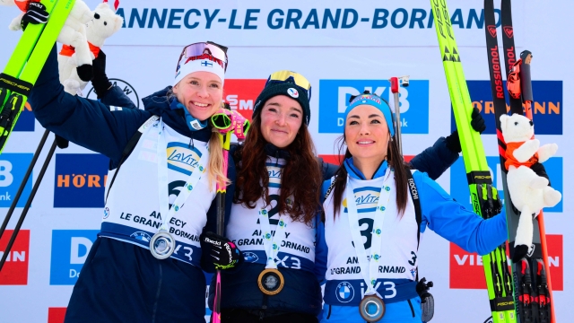 TOPSHOT - Second placed Finland's Suvi Minkkinen (L), first placed France's Lou Jeanmonnot and third placed Italy's Dorothea Wierer celebrate on the podium of the women's 10km pursuit event of the IBU Biathlon World Cup, in Le Grand Bornand, near Annecy, southeastern France, on December 20, 2025. (Photo by Olivier CHASSIGNOLE / AFP)