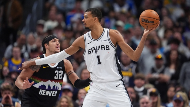 San Antonio Spurs center Victor Wembanyama, right, looks to pass the ball as Denver Nuggets forward Aaron Gordon defends during overtime of an NBA basketball game Saturday, April 4, 2026, in Denver. (AP Photo/David Zalubowski)