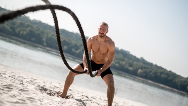 Strong man doing outside workout. Exercising with battle rope.