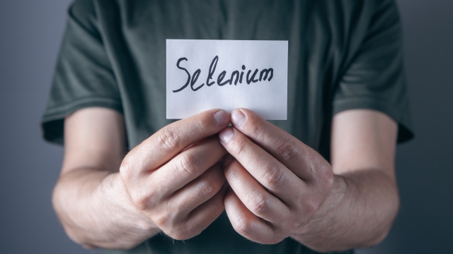 Man's hand holding a piece of paper with the word selenium