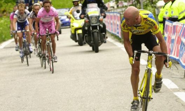 Marco Pantani al Giro nel 2003 davanti a Gilberto Simoni in maglia rosa. Dietro la moto ripresa e il cambio ruote. Ap