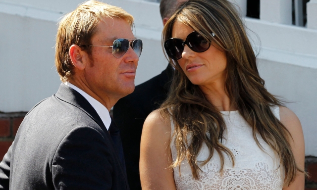 (FILES) In this file photograph taken on July 19, 2013, Australian former cricketer Shane Warne (L) with his fiancee British actress and model Liz Hurley are seen together after he is presented with an award during the tea interval on the second day of the second Ashes cricket test match between England and Australia at Lord's cricket ground in north London. - Australia cricket great Shane Warne, widely regarded as the greatest leg-spinner of all time, has died aged 52 according to a statement issued by his management company on March 4, 2022. Warne's management said he died in Koh Samui, Thailand, of a suspected heart attack. (Photo by Ian KINGTON / AFP)