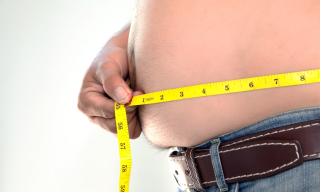 Obese person measuring his belly.