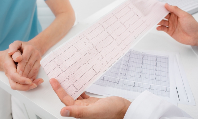 Doctor analyzes the electrocardiogram results, close-up. Diagnosis of arrhythmia, heart rate and heart disease