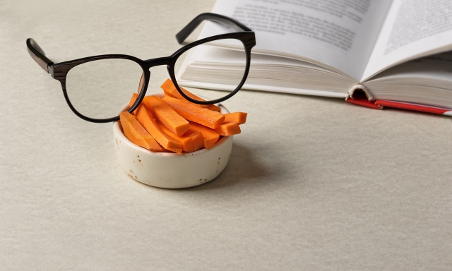natural vitamin A in fresh cut carrots with eyeglasses on the background of book