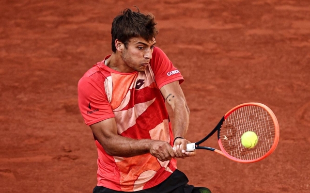 Italy's Flavio Cobolli plays a backhand return to Spain's Carlos Alcaraz Garfia during their men's singles match on day two of the Roland-Garros Open tennis tournament at the Court Suzanne-Lenglen in Paris on May 29, 2023. (Photo by Anne-Christine POUJOULAT / AFP)