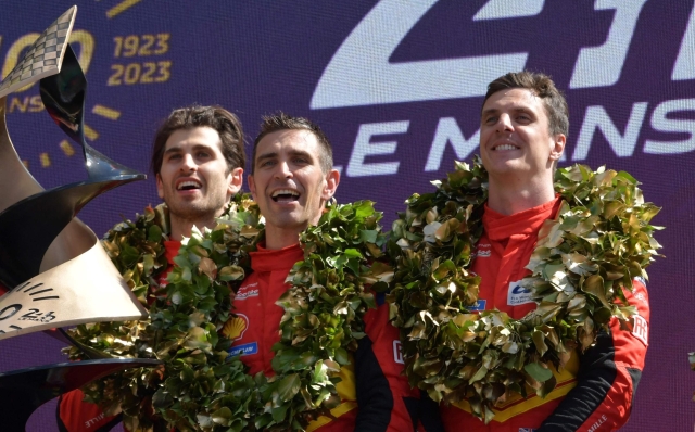 (From 2L) Ferrari N.51 499P Hypercar drivers Italian Antonio Giovinazzi, Italian Alessandro Pier Guidi and British James Calado celebrate on the podium after winning the endurance race 24 hours of Le Mans on June 11, 2023. This year marks the 100th anniversary of the race. (Photo by JEAN-FRANCOIS MONIER / AFP)
