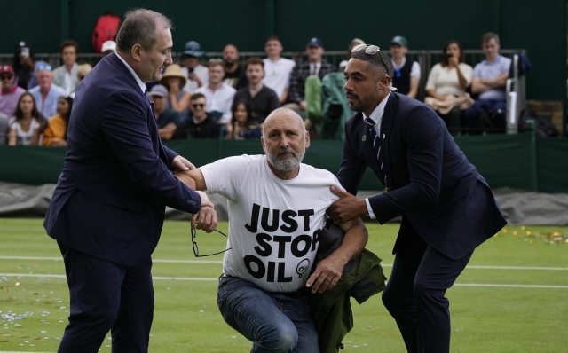 A Just Stop Oil protester is removed from Court 18 on day three of the Wimbledon tennis championships in London, Wednesday, July 5, 2023. (AP Photo/Alastair Grant)