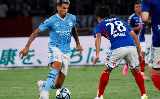 Manchester Citys defender Joao Cancelo (L) dribbles the ball in front of Yokohamas midfielder Riku Yamane during the J-League World Challenge 2023 football match between English Premier League champion Manchester City and Yokohama F-Marinos at the National Stadium in Tokyo on July 23, 2023. (Photo by Toshifumi KITAMURA / AFP)