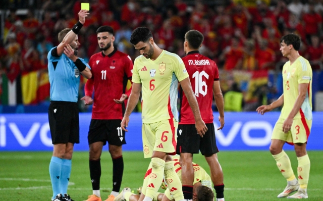 Swedish referee Glenn Nyberg (L) shows a yellow card to Albania's forward #16 Medon Berisha (C-R) as Spain's midfielder #06 Mikel Merino (C) looks on during the UEFA Euro 2024 Group B football match between Albania and Spain at the Duesseldorf Arena in Duesseldorf on June 24, 2024. (Photo by Alberto PIZZOLI / AFP)