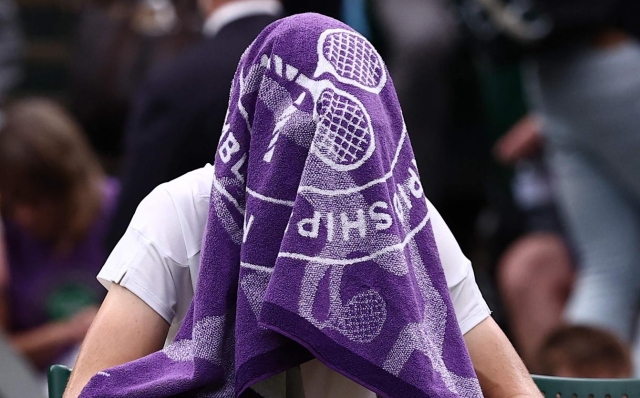 Italy's Jannik Sinner uses a towel during a break in play against Russia's Daniil Medvedev during their men's singles quarter-final tennis match on the ninth day of the 2024 Wimbledon Championships at The All England Lawn Tennis and Croquet Club in Wimbledon, southwest London, on July 9, 2024. (Photo by HENRY NICHOLLS / AFP) / RESTRICTED TO EDITORIAL USE
