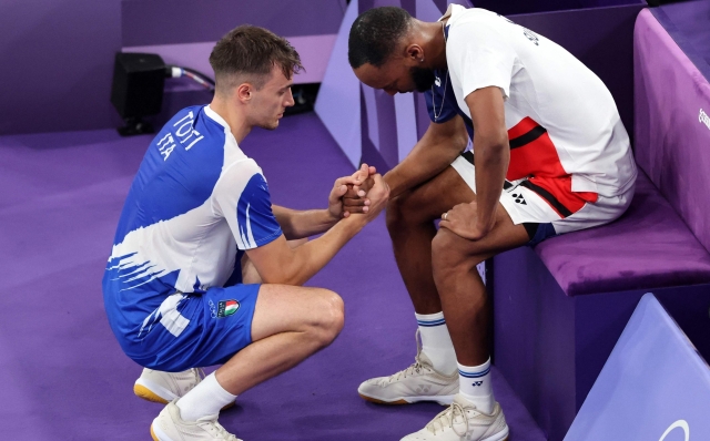Italy's Giovanni Toti consoles Suriname's Soren Opti as the latter withdraws from their men's singles badminton group stage match during the Paris 2024 Olympic Games at Porte de la Chapelle Arena in Paris on July 29, 2024. (Photo by David GRAY / AFP)