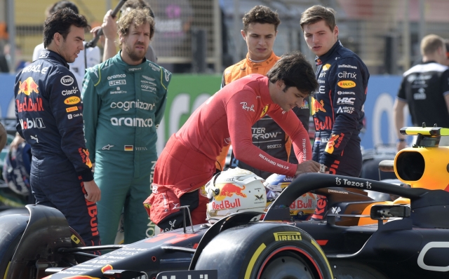 Ferrari's Spanish driver Carlos Sainz Jr (C) inspects the cockpit of Red Bull's Mexican driver Sergio Perez (L) as Aston Martin's German driver Sebastian Vettel (2nd-L), McLaren's British driver Lando Norris, and Red Bull's Dutch driver Max Verstappen (R) look on during the first day of Formula One (F1) pre-season testing at the Bahrain International Circuit in the city of Sakhir on March 12, 2021. (Photo by Mazen MAHDI / AFP)