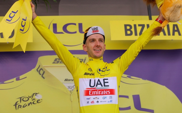 UAE Team Emirates' British rider Adam Yates celebrates on the podium with the overall leader's yellow jersey after the 1st stage of the 110th edition of the Tour de France cycling race, 182 km departing and finishing in Bilbao, in northern Spain, on July 1, 2023. (Photo by Thomas SAMSON / AFP)