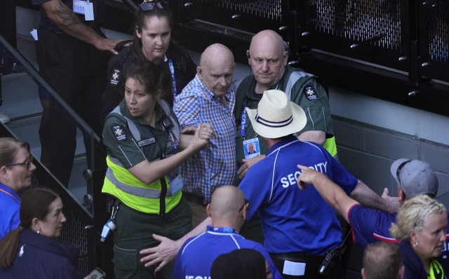 A spectator is assisted from Rod Laver Arena by medical staff during the semifinal between Novak Djokovic of Serbia and Jannik Sinner of Italy at the Australian Open tennis championships at Melbourne Park, Melbourne, Australia, Friday, Jan. 26, 2024. (AP Photo/Louise Delmotte)