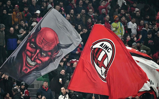 AC Milan's supporters wave giant flags before  the UEFA Europa League Last 16 first leg between AC Milan and Rennes at the San Siro Stadium in Milan. (Photo by GABRIEL BOUYS / AFP)