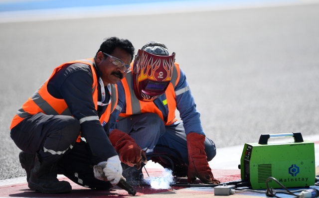 BAHRAIN, BAHRAIN - FEBRUARY 23: Track workers fix a loose drain cover that caused a red flag delay during day three of F1 Testing at Bahrain International Circuit on February 23, 2024 in Bahrain, Bahrain. (Photo by Rudy Carezzevoli/Getty Images)