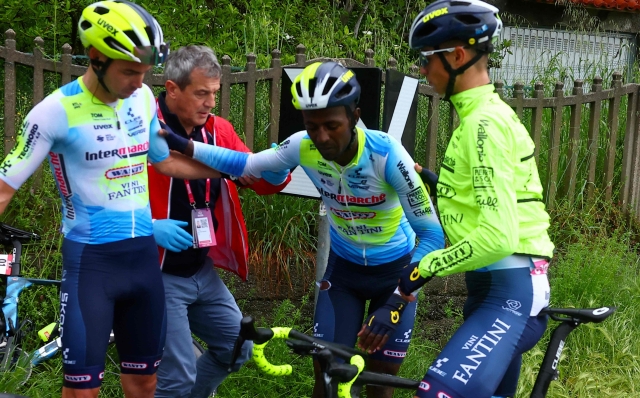 Team Intermarche's Eritrean rider Biniam Girmay (C) is helped by teammates after a fall during the 4th stage of the 107th Giro d'Italia cycling race, 190 km between Acqui Terme and Andora, on May 7, 2024 in Andora. (Photo by Luca Bettini / AFP)