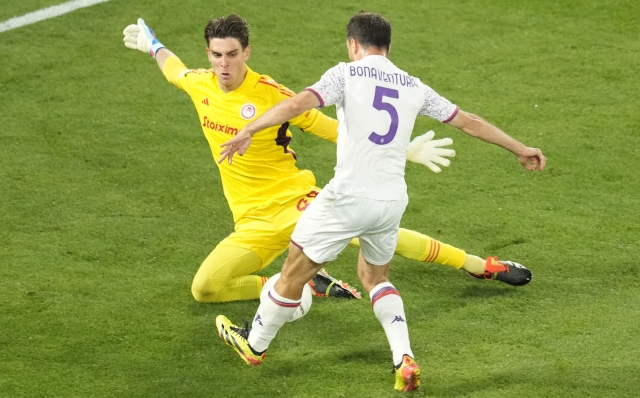 Olympiacos' goalkeeper Konstantinos Tzolakis challenges Fiorentina's Giacomo Bonaventura during the Conference League final soccer match between Olympiacos FC and ACF Fiorentina at OPAP Arena in Athens, Greece, Wednesday, May 29, 2024. (AP Photo/Petros Karadjias)
