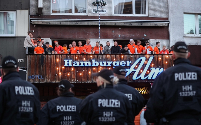 Netherlands supporters face German police officers as they gather at the famous Hamburg amusement mile "Reeperbahn" in Hamburg, northern Germany, on June 15, 2024, on the eve of the UEFA Euro 2024 football match between Poland and Netherlands. (Photo by Ronny Hartmann / AFP)