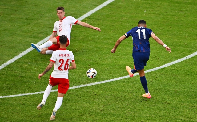HAMBURG, GERMANY - JUNE 16: Cody Gakpo of the Netherlands scores his team's first goal whilst under pressure from Taras Romanczuk and Kacper Urbanski of Poland during the UEFA EURO 2024 group stage match between Poland and Netherlands at Volksparkstadion on June 16, 2024 in Hamburg, Germany.   (Photo by Dan Mullan/Getty Images)
