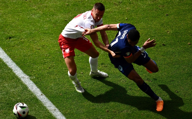 Poland's defender #19 Przemyslaw Frankowski (L) fights for the ball with Netherlands' forward #11 Cody Gakpo  during the UEFA Euro 2024 Group D football match between Poland and the Netherlands at the Volksparkstadion in Hamburg on June 16, 2024. (Photo by Christophe SIMON / AFP)