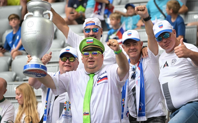 Fans of Slovenia celebrate in the tribune with a replica of the UEFA trophy prior to the UEFA Euro 2024 Group C football match between Slovenia and Serbia at the Munich Football Arena in Munich, southern Germany, on June 20, 2024. (Photo by DAMIEN MEYER / AFP)