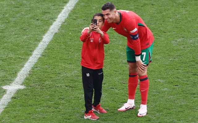 A pitch invader takes his selfie with Portugal's forward #07 Cristiano Ronaldo during the UEFA Euro 2024 Group F football match between Turkey and Portugal at the BVB Stadion in Dortmund on June 22, 2024. (Photo by KENZO TRIBOUILLARD / AFP)