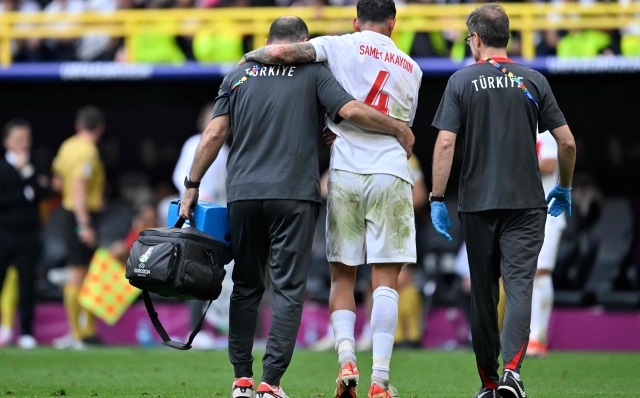 Turkey's defender #04 Samet Akaydin is helped from the pitch after picking up an injury during the UEFA Euro 2024 Group F football match between Turkey and Portugal at the BVB Stadion in Dortmund on June 22, 2024. (Photo by INA FASSBENDER / AFP)