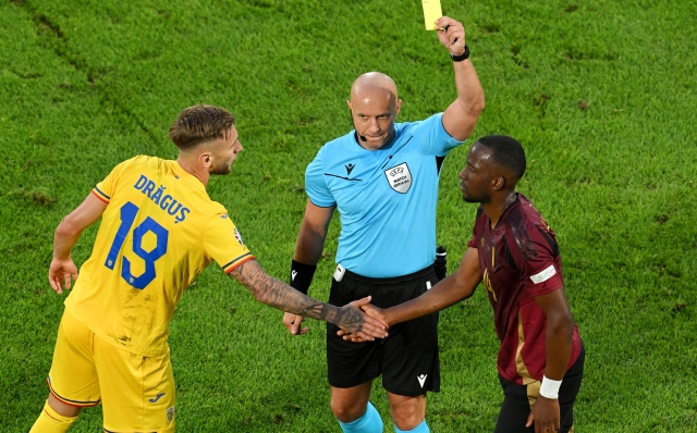 COLOGNE, GERMANY - JUNE 22: Dodi Lukebakio of Belgium is shown a yellow card by Referee Szymon Marciniak as he shakes the hand of Denis Dragus of Romania during the UEFA EURO 2024 group stage match between Belgium and Romania at Cologne Stadium on June 22, 2024 in Cologne, Germany. (Photo by Stu Forster/Getty Images)