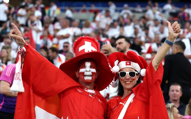 FRANKFURT AM MAIN, GERMANY - JUNE 23: Fans of Switzerland, wear face paint in the colours of the national flag, gesture as they enjoys the pre match atmosphere prior to the UEFA EURO 2024 group stage match between Switzerland and Germany at Frankfurt Arena on June 23, 2024 in Frankfurt am Main, Germany. (Photo by Alexander Hassenstein/Getty Images)
