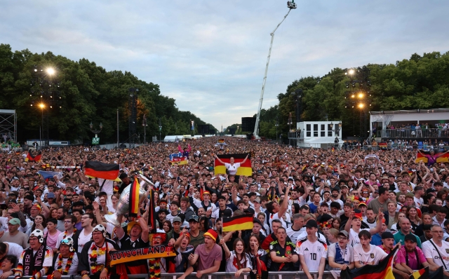 Football fans gather on June 23, 2024 in Berlin at the so-called Fanmeile (fan zone or fan mile) close to Berlin's landmark the Brandenburg Gate to watch the UEFA Euro 2024 Group A football match between Switzerland and Germany that is played in Frankfurt am Main. (Photo by Joerg CARSTENSEN / AFP)