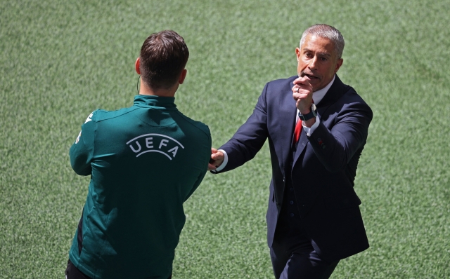 Albania's head coach Sylvinho (R) speaks with the fourth referee Swiss Sandro Schaerer (L) during the UEFA Euro 2024 Group B football match between Croatia and Albania at the Volksparkstadion in Hamburg on June 19, 2024. (Photo by Ronny HARTMANN / AFP)