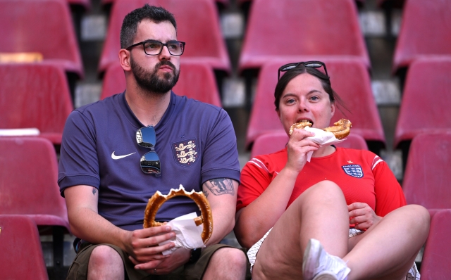 COLOGNE, GERMANY - JUNE 25: Fans of England look on, as they eat pretzels, on the inside of the stadium prior to the UEFA EURO 2024 group stage match between England and Slovenia at Cologne Stadium on June 25, 2024 in Cologne, Germany. (Photo by Stu Forster/Getty Images)