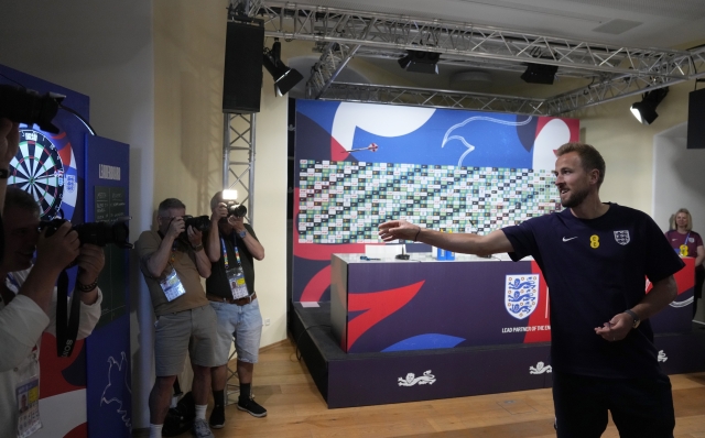 England's Harry Kane plays darts against a journalist before a press conference in Blankenhain, Germany, Sunday, June 23, 2024 ahead of the national team Group C soccer match against Slovenia at the Euro 2024 soccer tournament. (AP Photo/Thanassis Stavrakis)