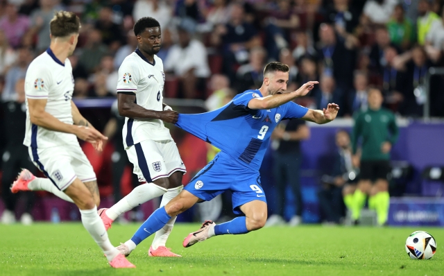 COLOGNE, GERMANY - JUNE 25: Andraz Sporar of Slovenia is fouled by Marc Guehi of England during the UEFA EURO 2024 group stage match between England and Slovenia at Cologne Stadium on June 25, 2024 in Cologne, Germany. (Photo by Alex Grimm/Getty Images)