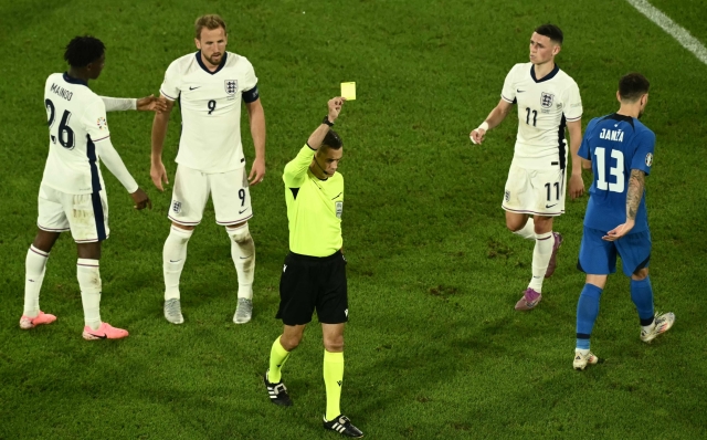 French referee Clement Turpin (C) shows a yellow card to Slovenia's defender #06 Jaka Bijol (unseen) next to England's midfielder #26 Kobbie Mainoo (L), England's forward #09 Harry Kane (2L), England's midfielder #11 Phil Foden (2R) and Slovenia's defender #13 Erik Janza (R) during the UEFA Euro 2024 Group C football match between England and Slovenia at the Cologne Stadium in Cologne on June 25, 2024. (Photo by Angelos Tzortzinis / AFP)