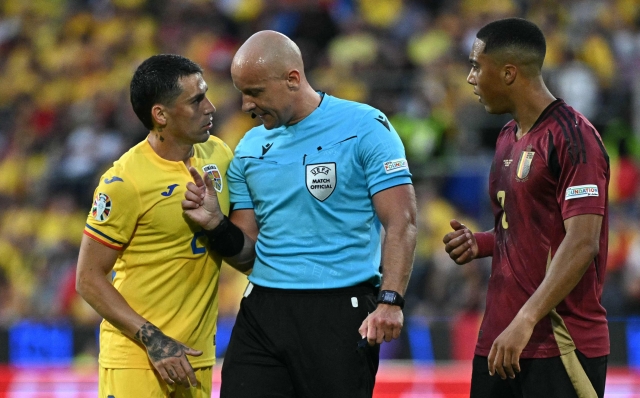 Polish referee Szymon Marciniak has words with Romania's midfielder #21 Nicolae Stanciu next to Belgium's midfielder #08 Youri Tielemans during the UEFA Euro 2024 Group E football match between Belgium and Romania at the Cologne Stadium in Cologne on June 22, 2024. (Photo by JAVIER SORIANO / AFP)