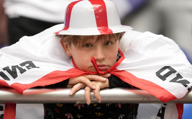 A young England fan on the stands waits for the start of a round of sixteen match between England and Slovakia at the Euro 2024 soccer tournament in Gelsenkirchen, Germany, Sunday, June 30, 2024. (AP Photo/Thanassis Stavrakis)