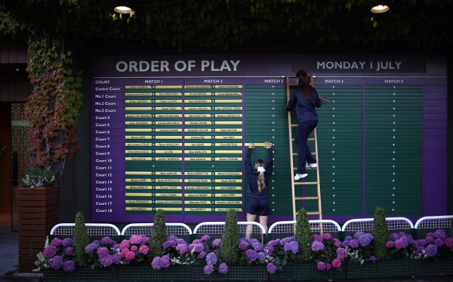 Workers set out the order of play on the first day of the 2024 Wimbledon Championships at The All England Lawn Tennis and Croquet Club in Wimbledon, southwest London, on July 1, 2024. (Photo by HENRY NICHOLLS / AFP) / RESTRICTED TO EDITORIAL USE