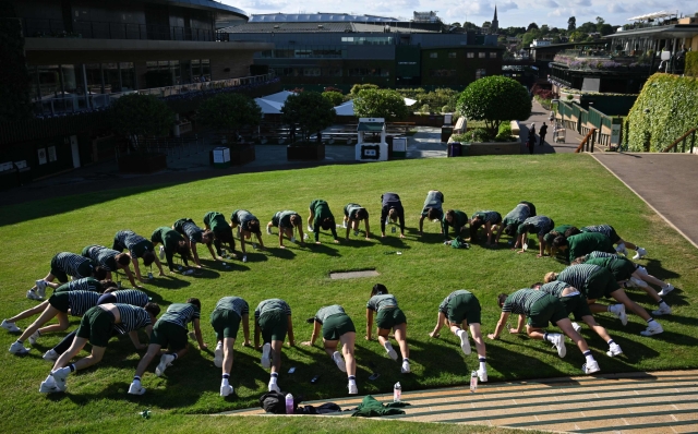 Groundstaff warm up on the first day of the 2024 Wimbledon Championships at The All England Lawn Tennis and Croquet Club in Wimbledon, southwest London, on July 1, 2024. (Photo by Glyn KIRK / AFP) / RESTRICTED TO EDITORIAL USE