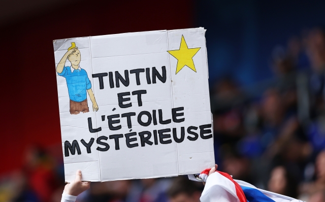 DUSSELDORF, GERMANY - JULY 01: A fan of France holds a sign which reads "Tintin and the Mysterious Star" as they enjoy the pre match atmosphere prior to the UEFA EURO 2024 round of 16 match between France and Belgium at Düsseldorf Arena on July 01, 2024 in Dusseldorf, Germany. (Photo by Carl Recine/Getty Images)