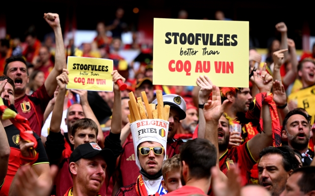 DUSSELDORF, GERMANY - JULY 01: A fan of Belgium, seen wearing a Belgian Fries novelty hat, poses for a photo as a sign which reads "Stoofvlees better than Coq Au Vin" can be seen, prior to the UEFA EURO 2024 round of 16 match between France and Belgium at Düsseldorf Arena on July 01, 2024 in Dusseldorf, Germany. (Photo by Clive Mason/Getty Images)