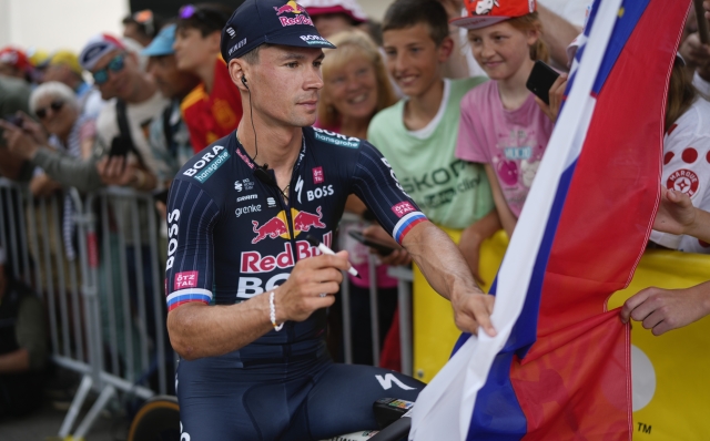 Slovenia's Primoz Roglic signs the national flag prior to the fifth stage of the Tour de France cycling race over 177.4 kilometers (110.2 miles) with start in Saint-Jean-de-Maurienne and finish in Saint-Vulbas, France, Wednesday, July 3, 2024. (AP Photo/Jerome Delay)