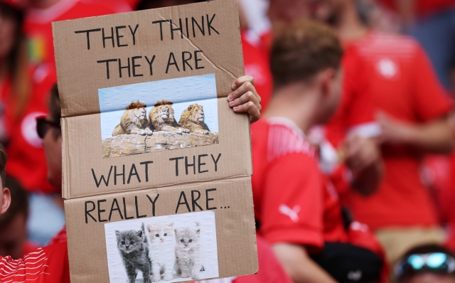 DUSSELDORF, GERMANY - JULY 06: A fan of Switzerland holds up a sign which reads "They think they are" which is followed by a picture of three lions, and "What they really are" which is followed by a picture of three kittens in the stands prior to the UEFA EURO 2024 quarter-final match between England and Switzerland at Düsseldorf Arena on July 06, 2024 in Dusseldorf, Germany. (Photo by Carl Recine/Getty Images)