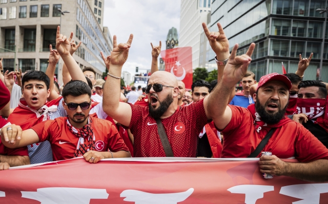 Turkey fans show the 'wolf salute', the origin of which is attributed to a right-wing extremist movement, during a fan walk before the start of the Euro 2024 quarterfinal soccer match between Netherlands and Turkey in Berlin, Saturday, July 6, 2024. (Christoph Soeder/dpa via AP)